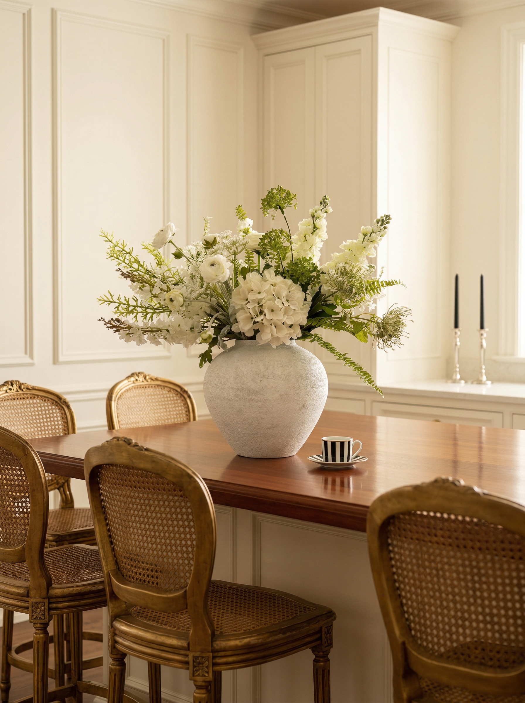Dining area with a table, chairs, and a large vase of flowers.