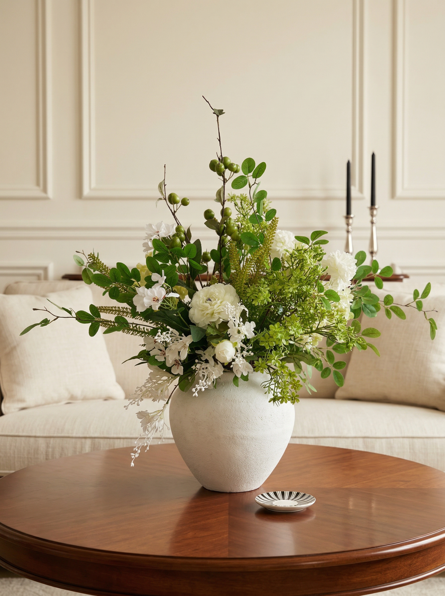 Floral arrangement in a white vase on a wooden coffee table with a neutral-colored wall in the background.