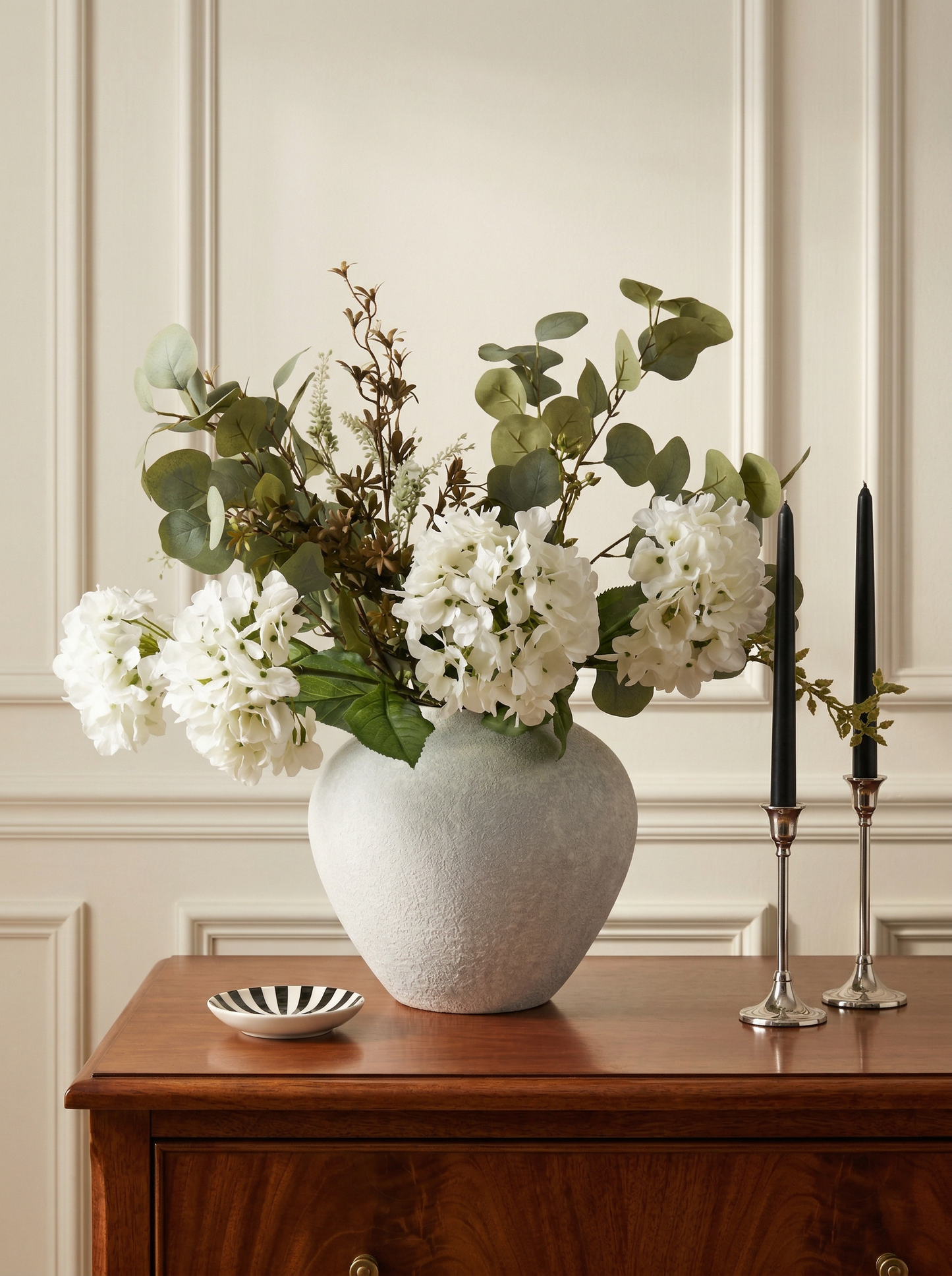 Vase with flowers on a wooden surface against a paneled wall